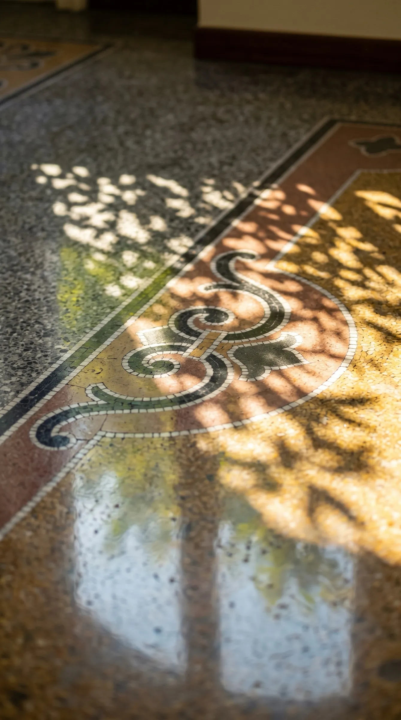 Pavimento d'epoca con motivi geometrici e floreali attraversato dalla luce del sole