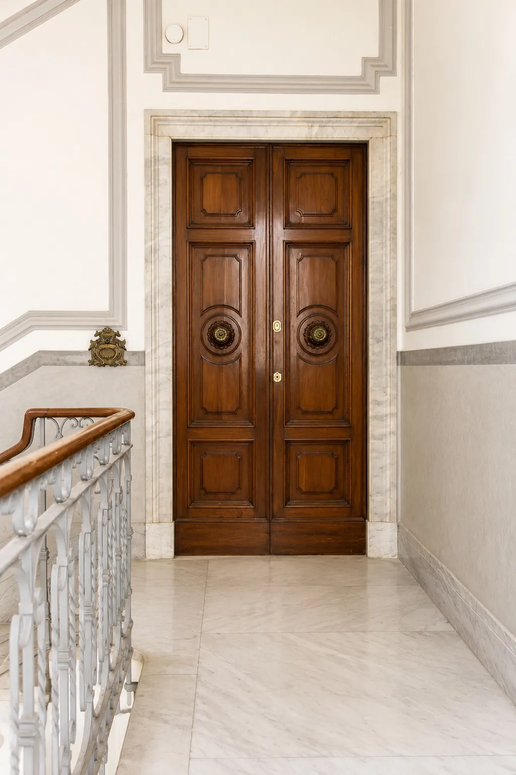 Portone a doppia anta in legno con battenti ad anello e cornice in marmo