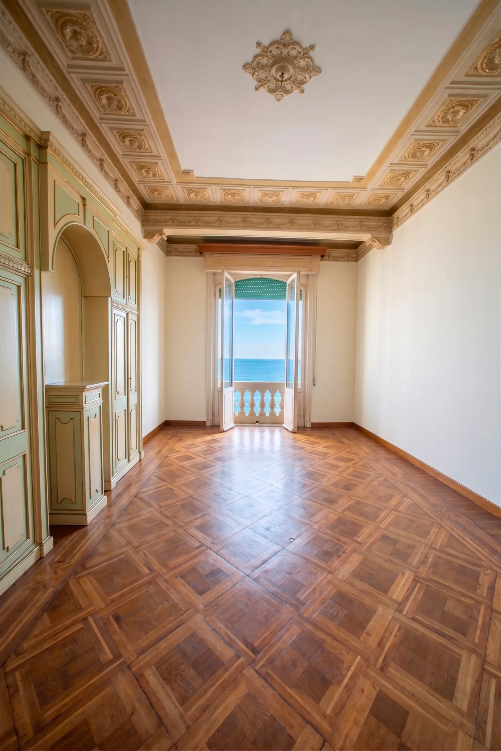 Sala d'epoca con soffitto a cassettoni, boiserie e portafinestra sul mare